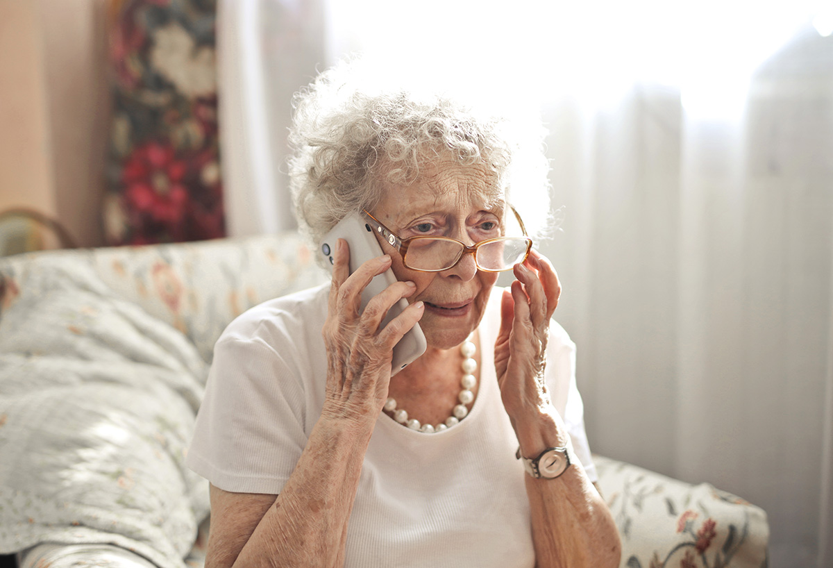 ltere Dame mit besorgtem Blick beim Telefonieren